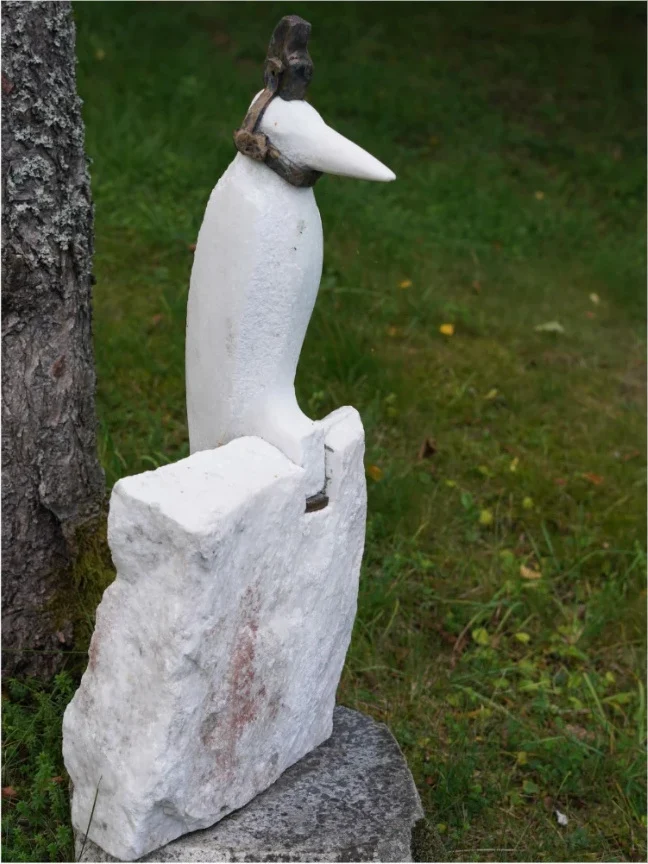 Bird sculpture in white stone in a garden